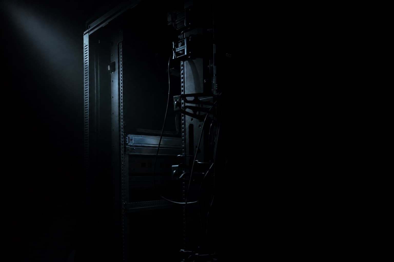 A single server in a rack under work lighting, drive bays open and one drive part-way out